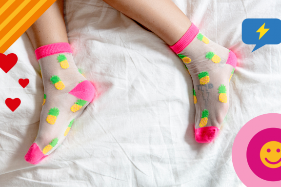 Füße mit bunten Socken im Bett